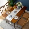 Table runner Camilla putih dengan motif floral sebagai dekorasi meja makan