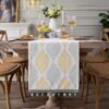 Table runner Vasa warna kuning dengan motif daun di meja makan